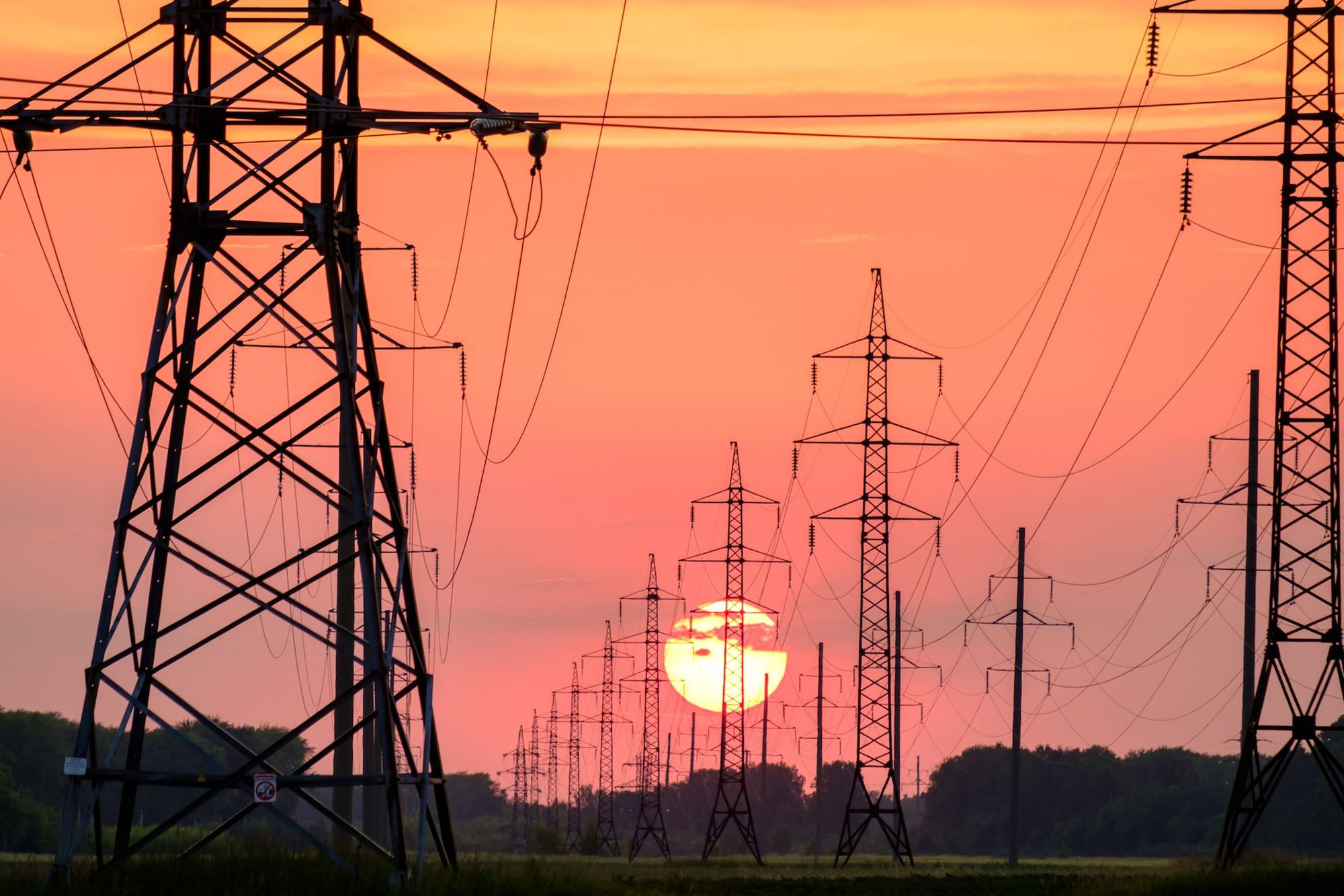 Hochspannungsmasten einer Energieübertragungstrasse in der Abenddämmerung